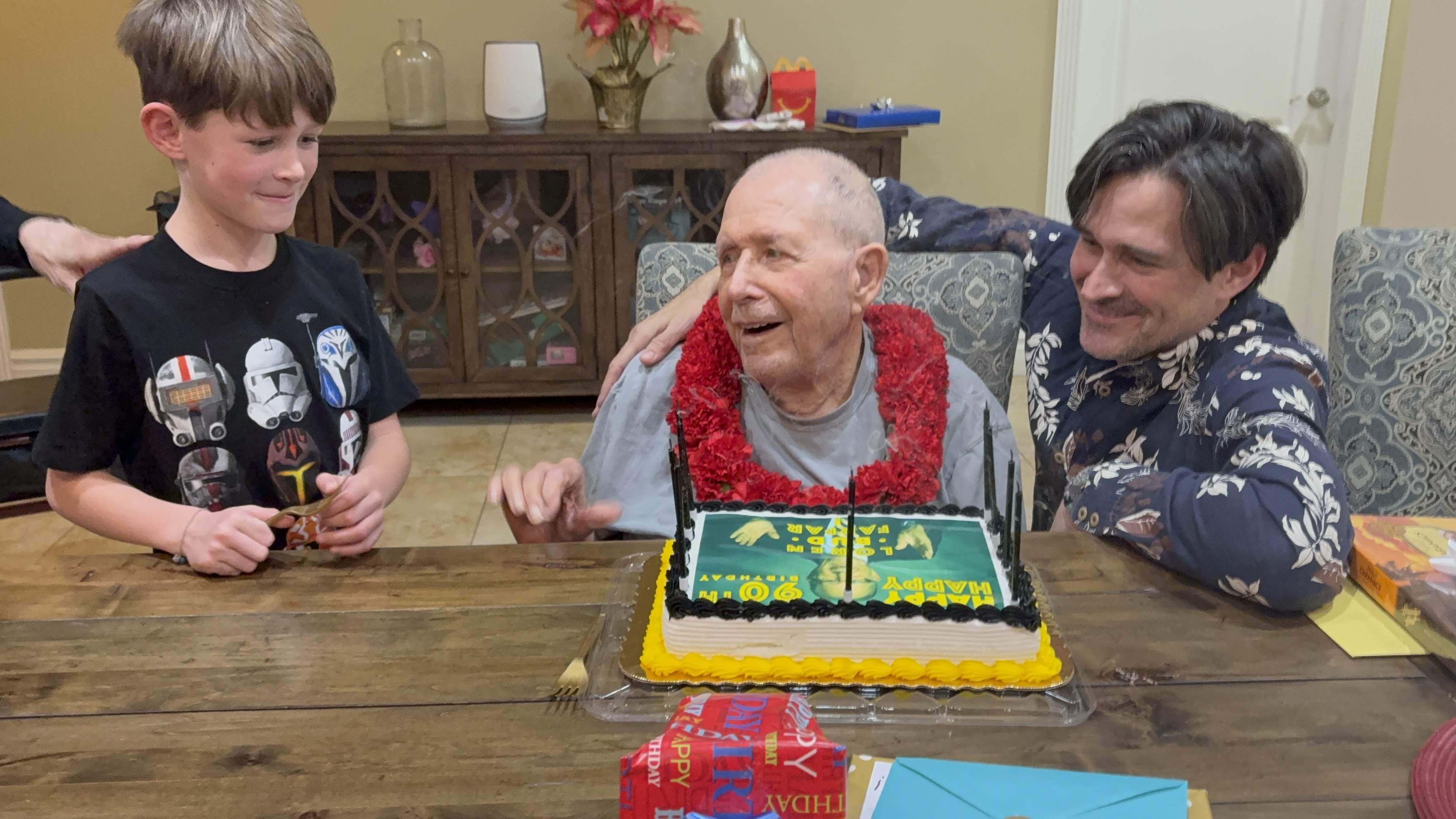 90th birthday with grandson Anders and son Aaron. The cake reads “Loren · Bud · Farfar” — Bud because two-year-old Cynthia couldn’t say “brother” and called him her “budder.”